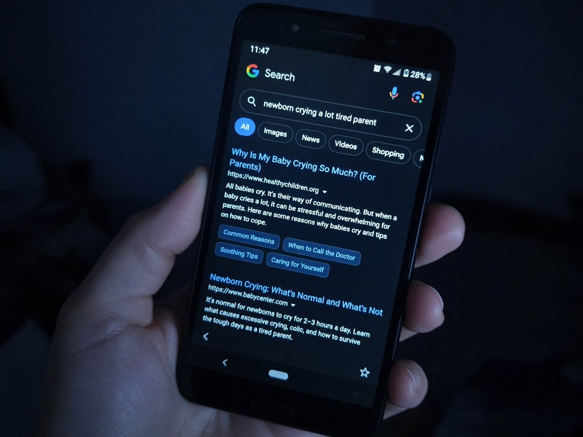 Parent googling newborn symptoms on phone at night
